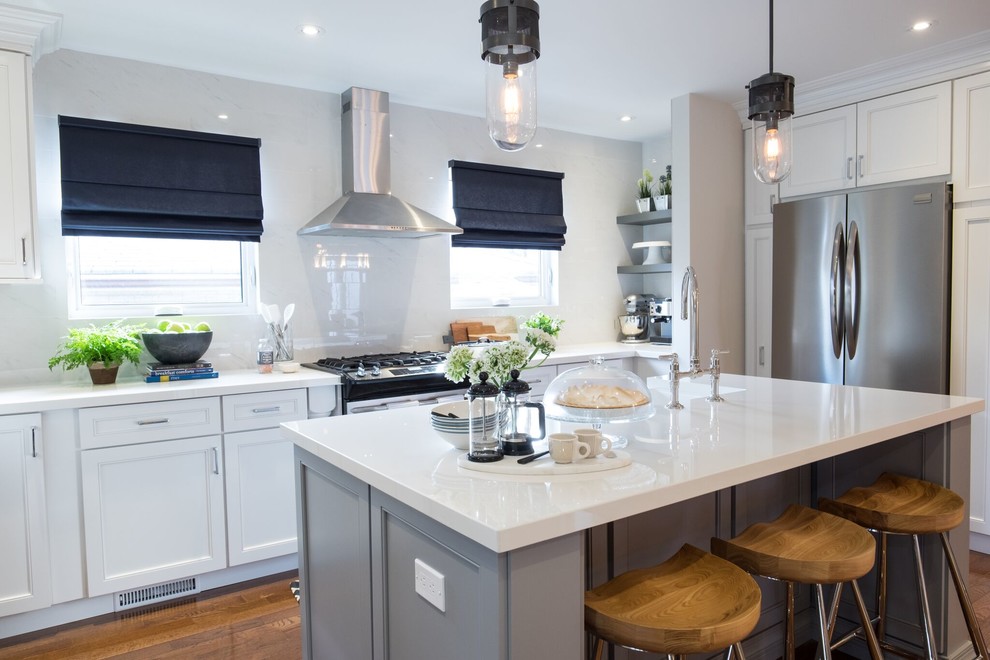This is an example of a small transitional eat-in kitchen in Toronto with a farmhouse sink, white cabinets, white splashback, stainless steel appliances, medium hardwood floors, with island and brown floor.