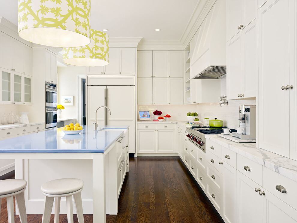 Photo of a contemporary l-shaped kitchen in San Francisco with a farmhouse sink, recessed-panel cabinets, white cabinets, white splashback, subway tile splashback, panelled appliances and blue benchtop.