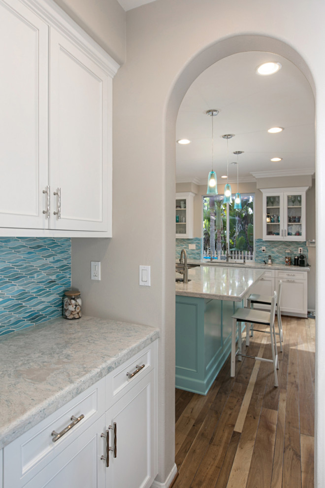 Inspiration for a mid-sized contemporary l-shaped home bar in San Diego with beaded inset cabinets, white cabinets, quartzite benchtops, blue splashback, glass tile splashback, light hardwood floors, beige floor, white benchtop and an undermount sink.