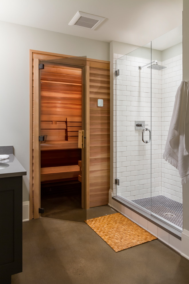 Photo of a large transitional bathroom in Minneapolis with shaker cabinets, grey cabinets, white tile, ceramic tile, grey walls, concrete floors, with a sauna, an undermount sink, engineered quartz benchtops, grey floor and a hinged shower door.