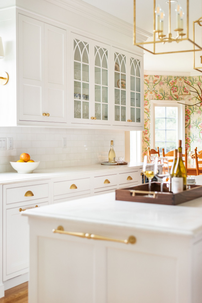 Foto på ett stort vintage vit u-kök, med vita skåp, marmorbänkskiva och en köksö
