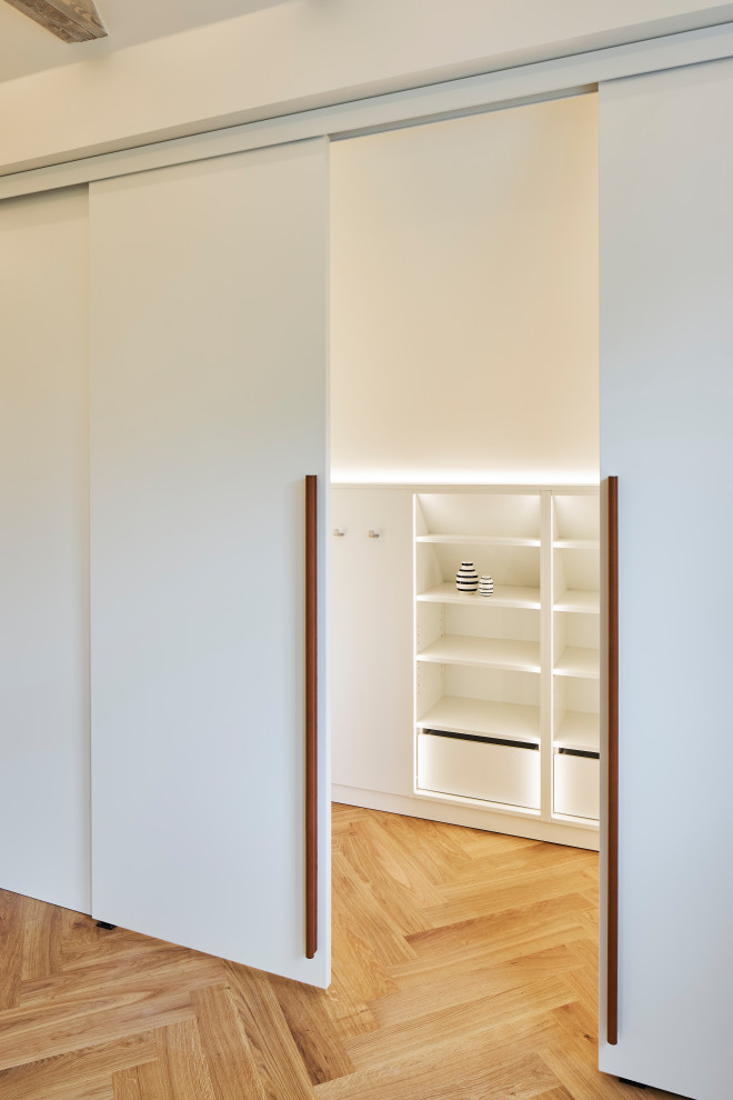Immagine di una cameretta neutra moderna di medie dimensioni con pareti bianche, pavimento in legno massello medio e travi a vista