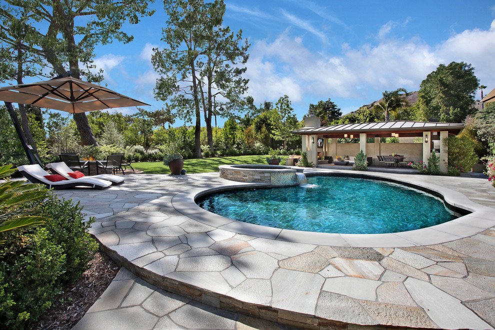 Design ideas for a contemporary custom-shaped pool in Orange County with natural stone pavers.