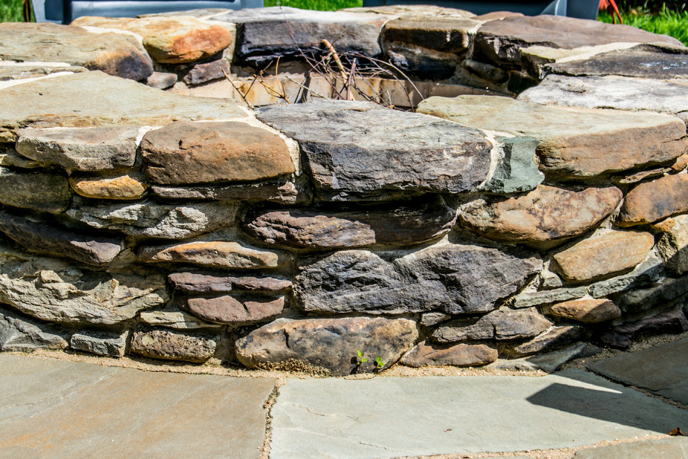 Design ideas for a rustic backyard stone landscaping in Chicago with a fire pit.