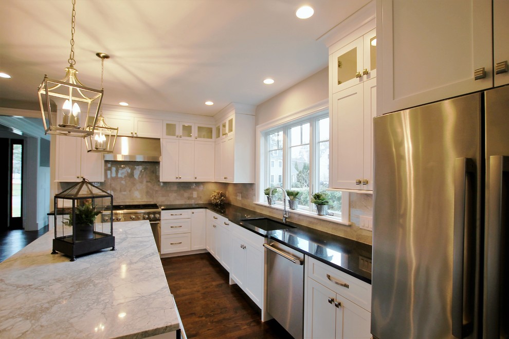Eat-in kitchen - large transitional l-shaped dark wood floor and brown floor eat-in kitchen idea in Boston with an undermount sink, shaker cabinets, white cabinets, granite countertops, beige backsplash, marble backsplash, stainless steel appliances and an island