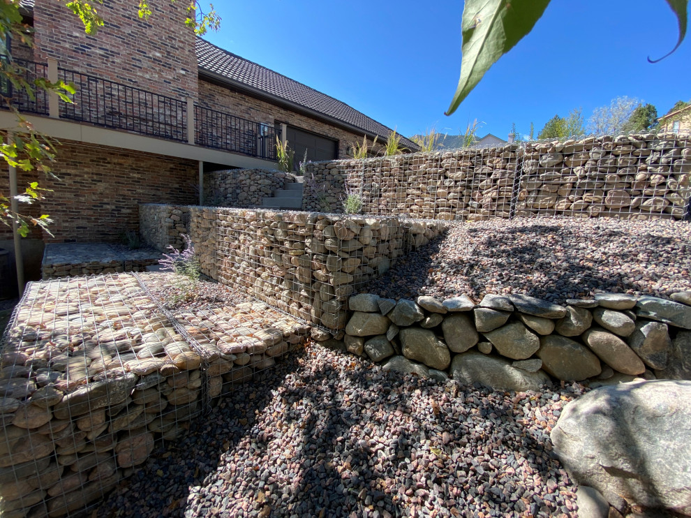 Inspiration for a mid-sized traditional backyard partial sun driveway in Denver with a retaining wall and river rock.