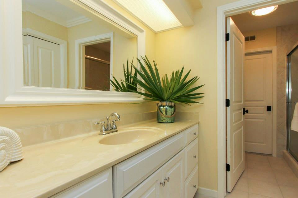 Mid-sized beach style master bathroom in Other with raised-panel cabinets, white cabinets, an alcove shower, a two-piece toilet, beige tile, porcelain tile, yellow walls, porcelain floors, an integrated sink, solid surface benchtops, beige floor, a hinged shower door, yellow benchtops, a single vanity and a built-in vanity.