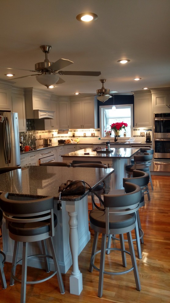 Eat-in kitchen - huge transitional light wood floor eat-in kitchen idea in Boston with a single-bowl sink, beaded inset cabinets, gray cabinets, quartz countertops, multicolored backsplash, glass tile backsplash, stainless steel appliances and two islands
