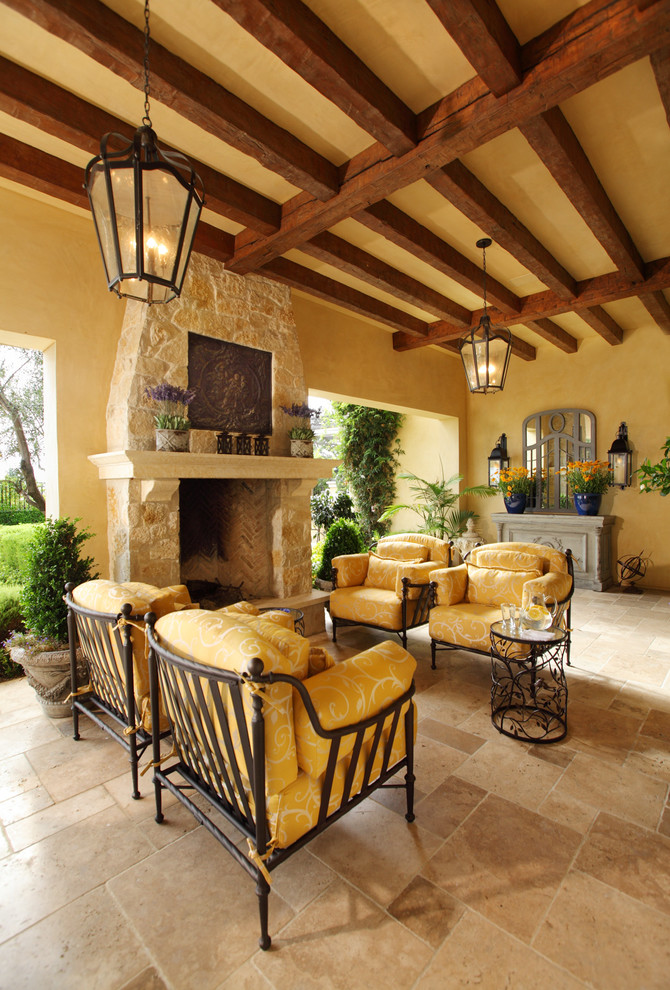 Design ideas for a mediterranean patio in Orange County with tile, a roof extension and with fireplace.