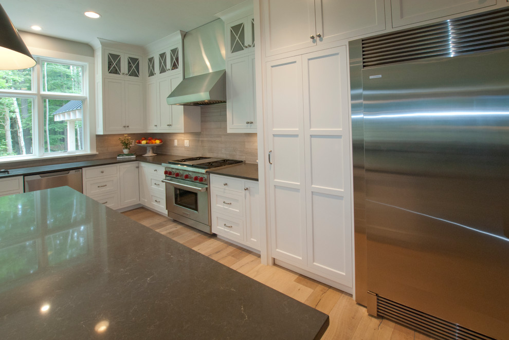 Example of a mid-sized transitional l-shaped light wood floor and beige floor eat-in kitchen design with an undermount sink, shaker cabinets, white cabinets, solid surface countertops, multicolored backsplash, porcelain backsplash, stainless steel appliances and an island
