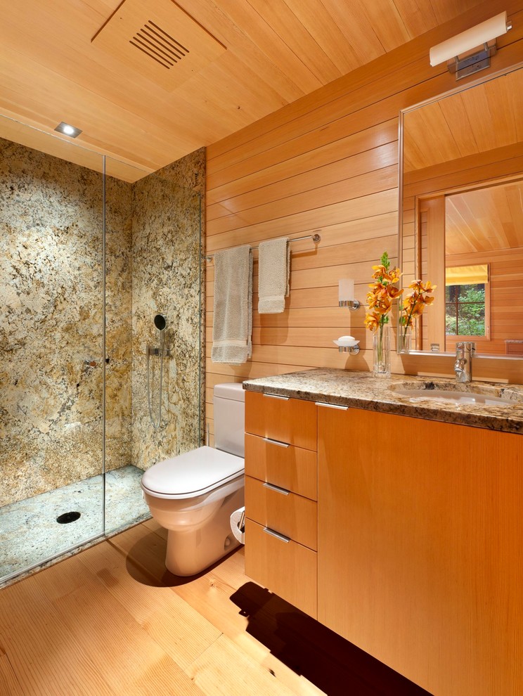 Photo of a small transitional 3/4 bathroom in Portland Maine with an undermount sink, flat-panel cabinets, granite benchtops, an alcove shower, a two-piece toilet, brown tile, medium hardwood floors and medium wood cabinets.