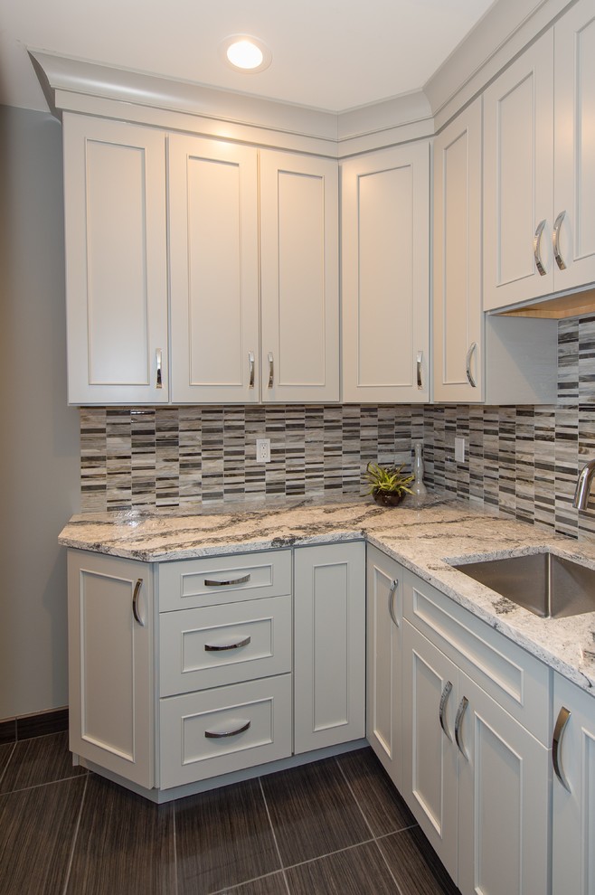 Design ideas for a mid-sized transitional l-shaped laundry room in Grand Rapids with an undermount sink, white cabinets, quartz benchtops and recessed-panel cabinets.