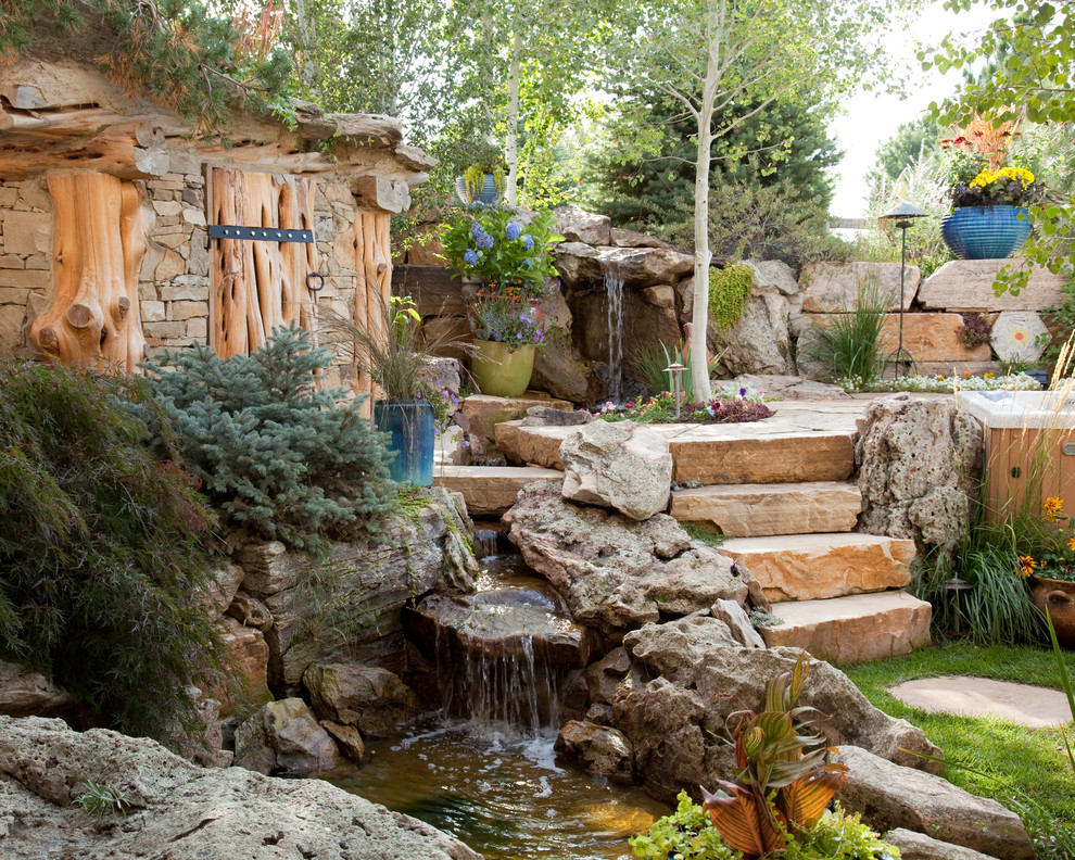 Inspiration for a large traditional backyard partial sun formal garden in Denver with a water feature and natural stone pavers.