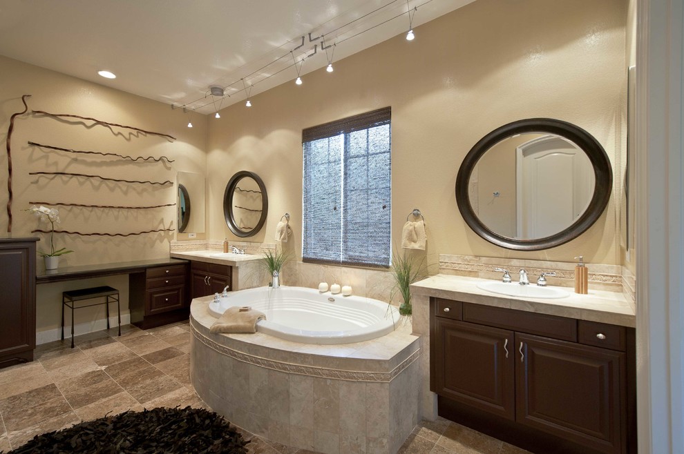 This is an example of a mid-sized transitional master bathroom in San Diego with raised-panel cabinets, brown cabinets, a drop-in tub, a double shower, a one-piece toilet, beige tile, porcelain tile, beige walls, marble floors, a drop-in sink, tile benchtops, brown floor, a hinged shower door and beige benchtops.