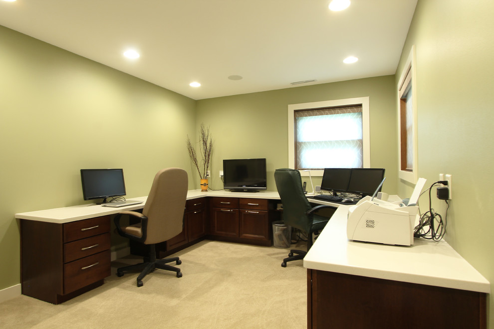 This is an example of a mid-sized transitional home office in Other with green walls, carpet, a built-in desk and beige floor.