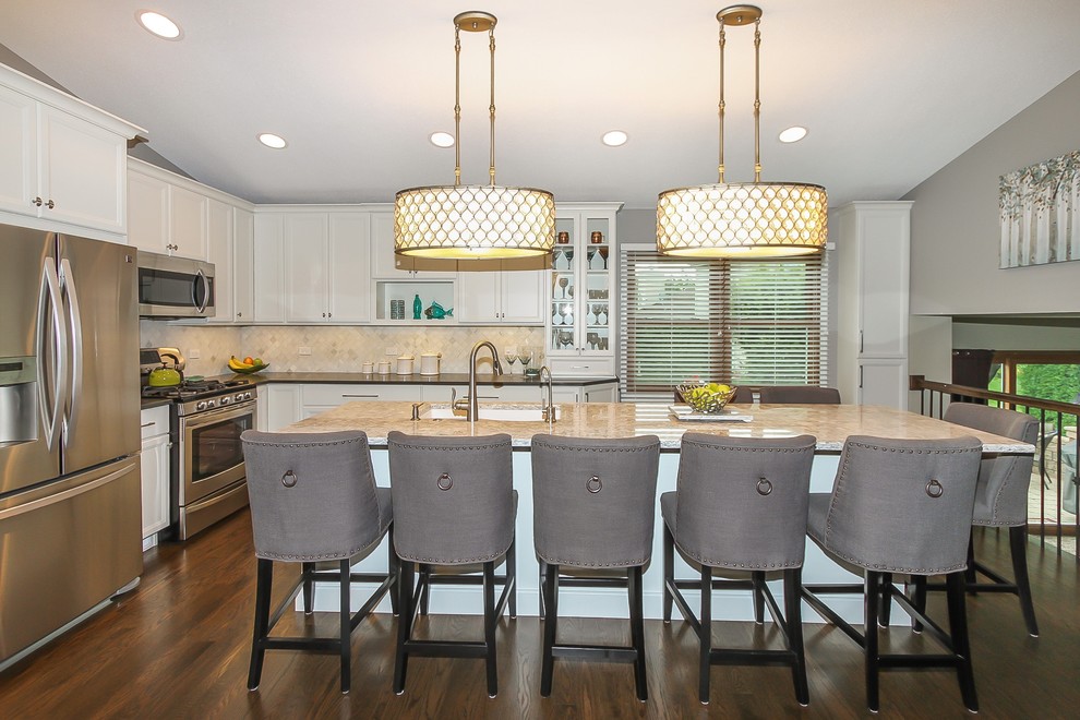 Eat-in kitchen - mid-sized transitional l-shaped dark wood floor and brown floor eat-in kitchen idea in Chicago with flat-panel cabinets, white cabinets, quartz countertops, beige backsplash, stone tile backsplash, stainless steel appliances, an island and a single-bowl sink