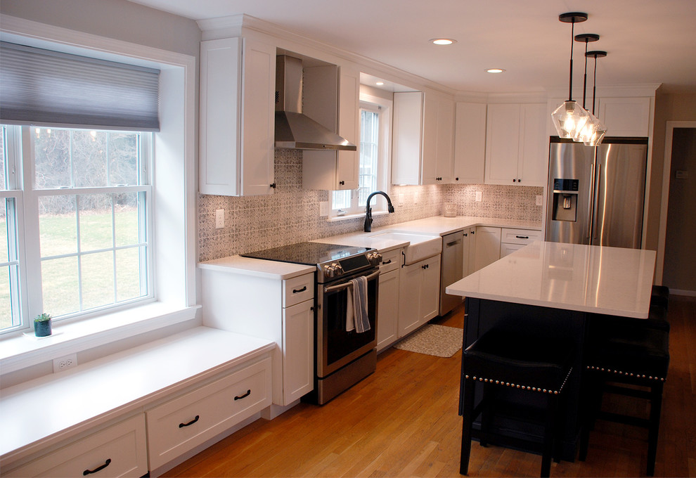 Photo of a mid-sized traditional u-shaped eat-in kitchen in Boston with a farmhouse sink, shaker cabinets, white cabinets, marble benchtops, multi-coloured splashback, slate splashback, stainless steel appliances, light hardwood floors, with island, brown floor and white benchtop.