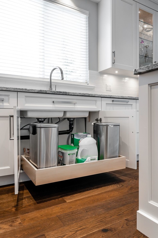 Large transitional u-shaped medium tone wood floor and brown floor eat-in kitchen photo in Vancouver with an undermount sink, recessed-panel cabinets, white cabinets, granite countertops, white backsplash, subway tile backsplash, stainless steel appliances, an island and multicolored countertops