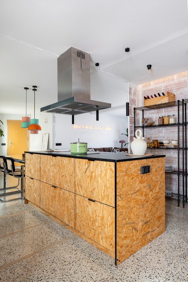 Inspiration for a mid-sized industrial open plan kitchen in Barcelona with an undermount sink, raised-panel cabinets, medium wood cabinets, granite benchtops, black splashback, granite splashback, stainless steel appliances, ceramic floors, with island, grey floor and black benchtop.