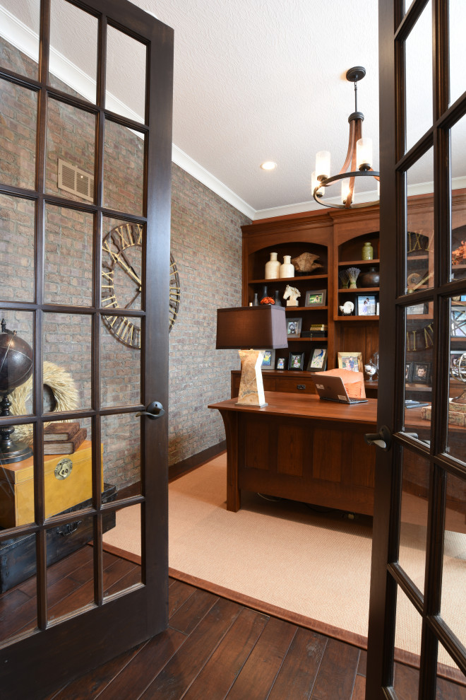 Inspiration for a mid-sized transitional study room in New York with beige walls, dark hardwood floors, a freestanding desk, brown floor and brick walls.