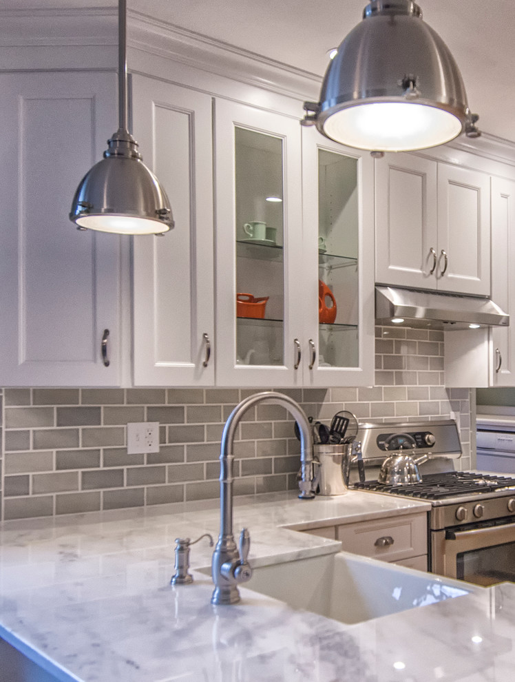 Inspiration for a mid-sized transitional u-shaped medium tone wood floor and brown floor eat-in kitchen remodel in Bridgeport with a farmhouse sink, recessed-panel cabinets, white cabinets, marble countertops, gray backsplash, subway tile backsplash, stainless steel appliances and a peninsula