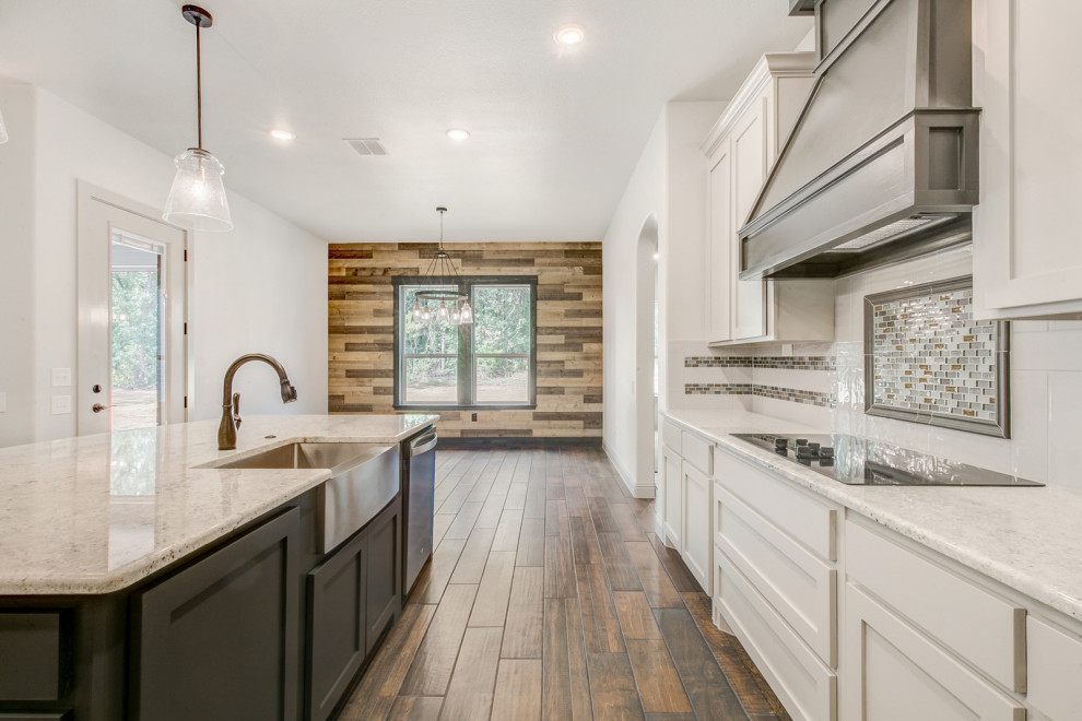 Photo of a large u-shaped eat-in kitchen in Dallas with recessed-panel cabinets, white cabinets, limestone benchtops, white splashback, subway tile splashback, stainless steel appliances, porcelain floors, with island, brown floor and white benchtop.