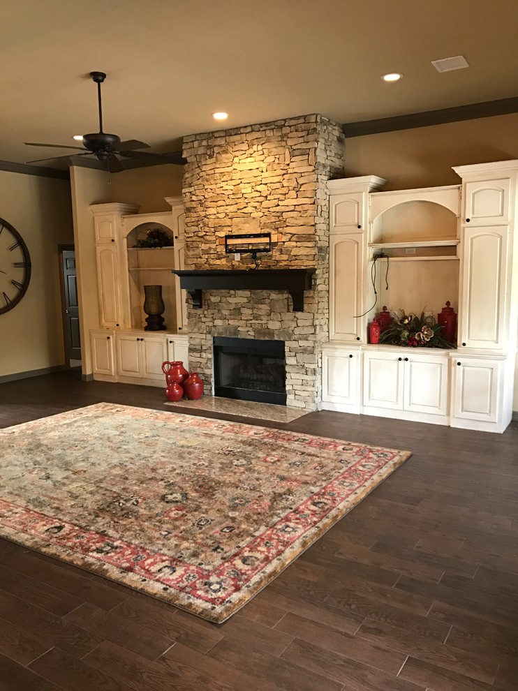 Photo of a mid-sized traditional open concept family room in Houston with beige walls, ceramic floors, a standard fireplace, a stone fireplace surround, a wall-mounted tv and brown floor.