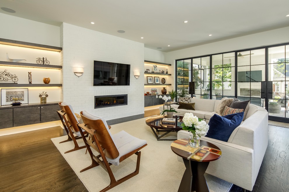Large contemporary formal open concept living room in Atlanta with white walls, medium hardwood floors, a ribbon fireplace, a brick fireplace surround, a wall-mounted tv and brown floor.