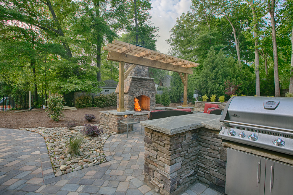 This is an example of a large arts and crafts backyard patio in Charlotte with a fire feature, concrete pavers and a pergola.