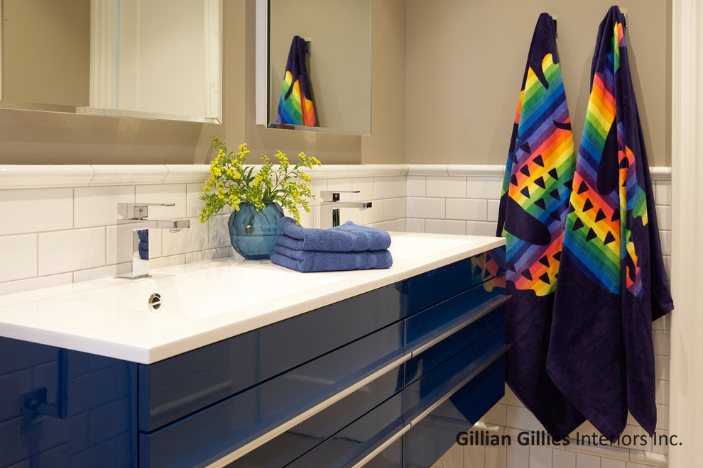 This is an example of a mid-sized contemporary kids bathroom in Toronto with an integrated sink, flat-panel cabinets, blue cabinets, quartzite benchtops, a drop-in tub, a shower/bathtub combo, a two-piece toilet, white tile, porcelain tile, beige walls and limestone floors.