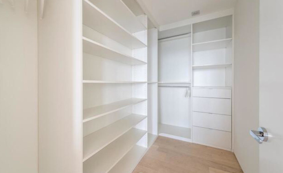 Inspiration for a large modern gender-neutral walk-in wardrobe in Miami with flat-panel cabinets, white cabinets, porcelain floors and beige floor.