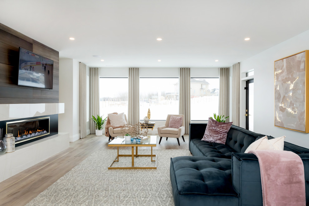 Стильный дизайн: огромная гостиная комната в современном стиле с белыми стенами, светлым паркетным полом, двусторонним камином, телевизором на стене и коричневым полом - последний тренд