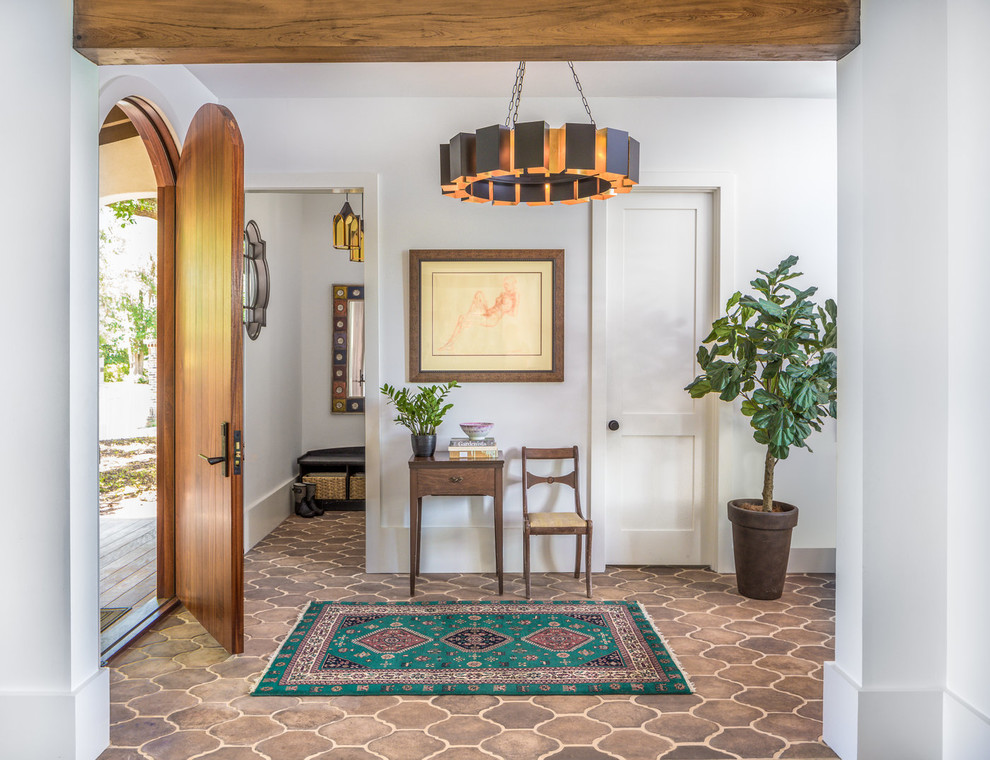 This is an example of a mediterranean foyer in Charleston with white walls, a single front door, a medium wood front door and brown floor.