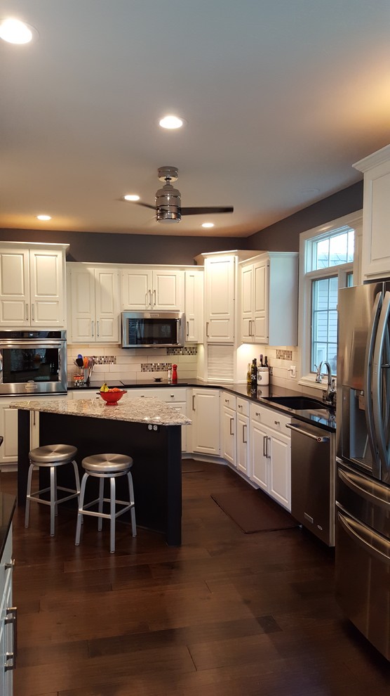Inspiration for a mid-sized transitional l-shaped kitchen in Other with an undermount sink, raised-panel cabinets, white cabinets, granite benchtops, white splashback, subway tile splashback, stainless steel appliances, medium hardwood floors, with island and brown floor.