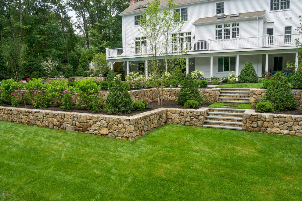 This is an example of a large traditional full sun backyard stone retaining wall landscape in Boston.