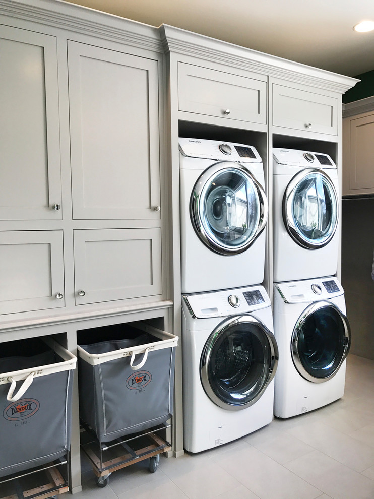 Photo of an expansive transitional u-shaped utility room in Other with green walls and a stacked washer and dryer.