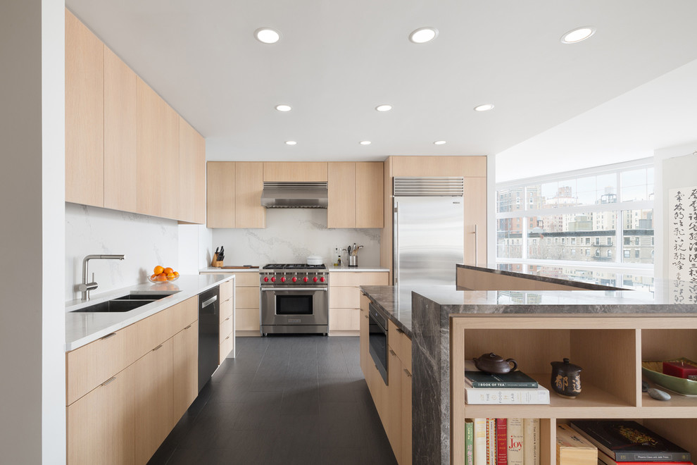 Contemporary kitchen in New York with a double-bowl sink, flat-panel cabinets, light wood cabinets, white splashback, stone slab splashback, stainless steel appliances, with island, grey floor and white benchtop.