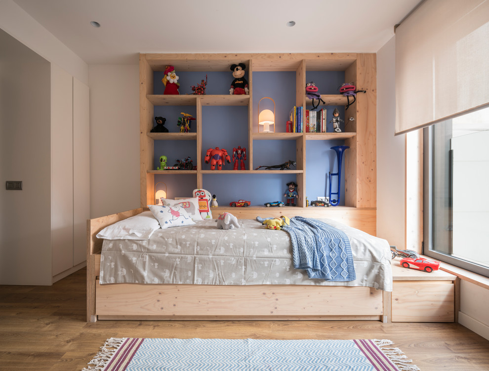 This is an example of a mid-sized contemporary gender-neutral kids' bedroom for kids 4-10 years old in Barcelona with blue walls, medium hardwood floors and brown floor.