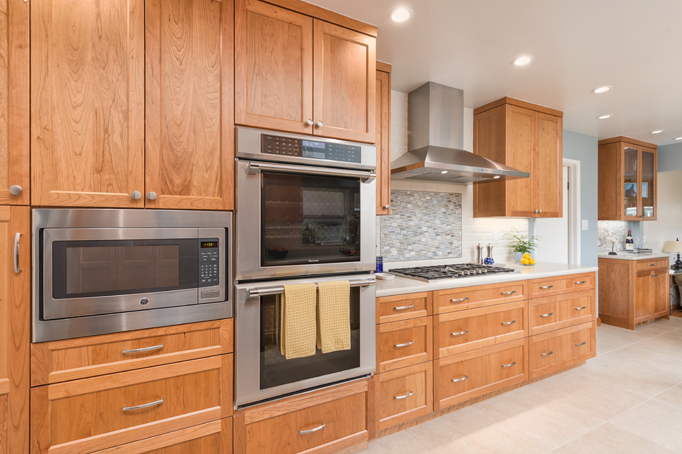 This is an example of a mid-sized transitional u-shaped eat-in kitchen in San Francisco with shaker cabinets, light wood cabinets, quartz benchtops, white splashback, subway tile splashback, stainless steel appliances, ceramic floors, a peninsula, beige floor and white benchtop.