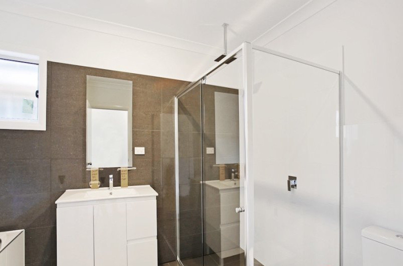 Photo of a mid-sized contemporary bathroom in Sydney with furniture-like cabinets, white cabinets, a corner shower, brown tile, porcelain tile, porcelain floors and a drop-in tub.