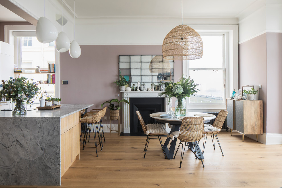 Design ideas for a large scandinavian kitchen/dining combo in Sussex with pink walls, light hardwood floors, a standard fireplace, a stone fireplace surround, brown floor and coffered.