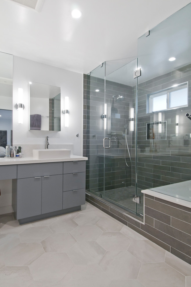Large contemporary master bathroom in Los Angeles with glass-front cabinets, grey cabinets, a corner shower, gray tile, porcelain tile, grey walls, cement tiles, a vessel sink, solid surface benchtops, grey floor, a hinged shower door and white benchtops.