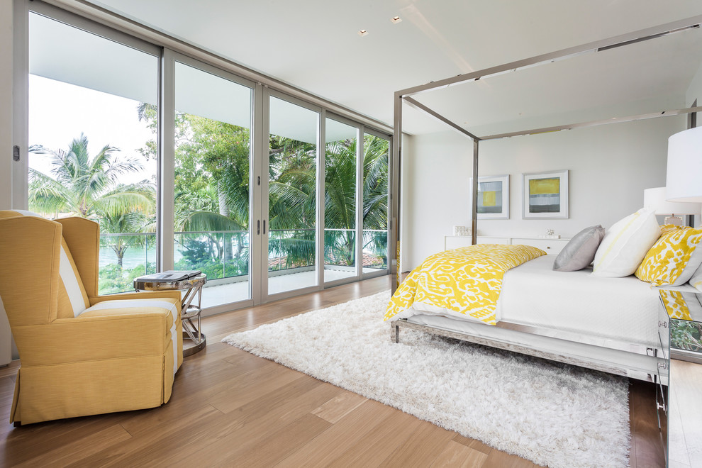 This is an example of a contemporary bedroom in Miami with white walls and medium hardwood floors.