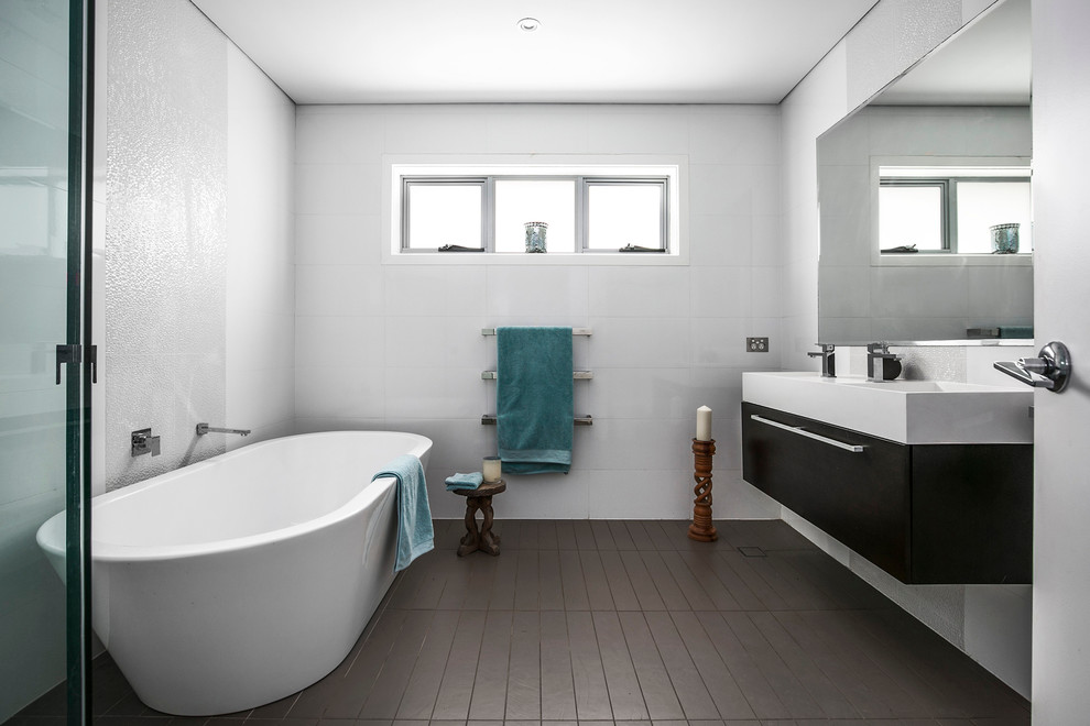 Mid-sized contemporary master bathroom in Sydney with flat-panel cabinets, a freestanding tub, an alcove shower, white walls, solid surface benchtops, brown floor, a hinged shower door, black cabinets, an integrated sink and white benchtops.