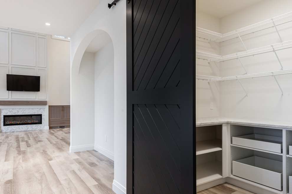 Inspiration for a mid-sized transitional l-shaped laminate floor and brown floor eat-in kitchen remodel in Toronto with an undermount sink, recessed-panel cabinets, black cabinets, quartz countertops, white backsplash, ceramic backsplash, stainless steel appliances, an island and white countertops