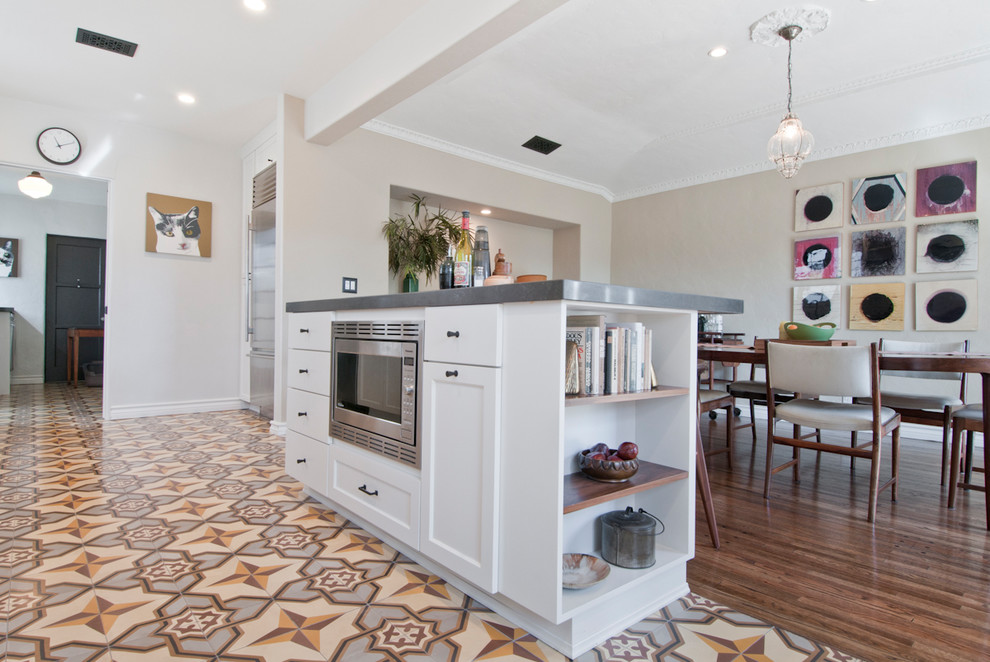 This is an example of a mid-sized transitional galley open plan kitchen in Los Angeles with an undermount sink, shaker cabinets, white cabinets, quartzite benchtops, white splashback, ceramic splashback, stainless steel appliances, cement tiles, with island and multi-coloured floor.