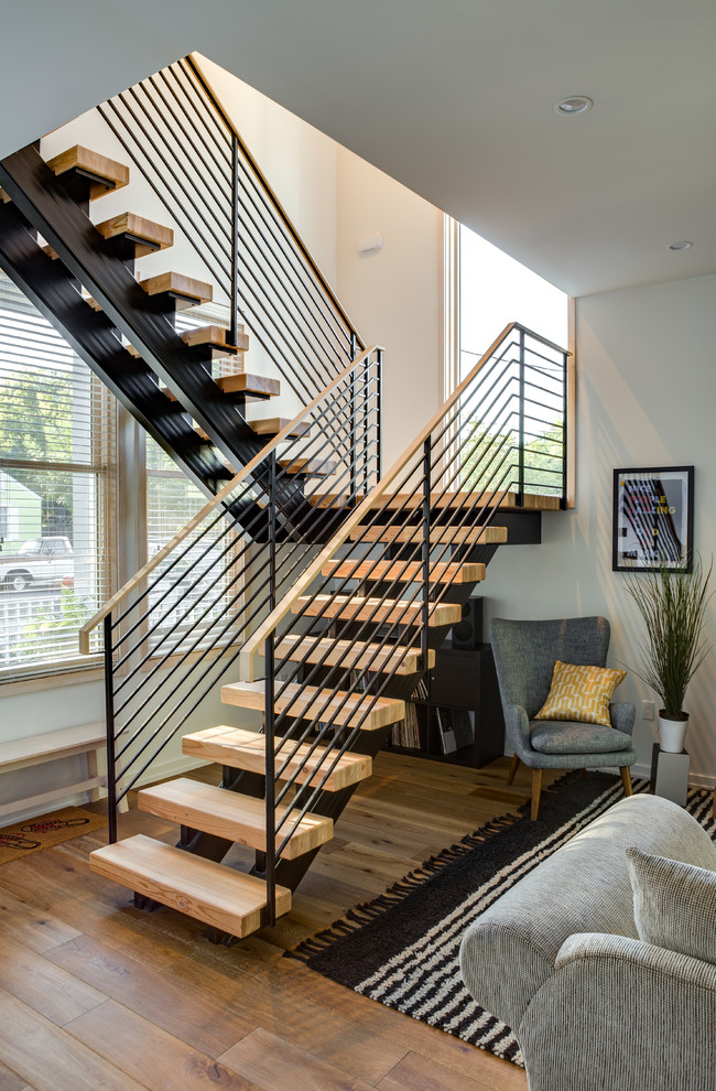 Photo of a transitional wood u-shaped staircase in Austin with open risers and metal railing.