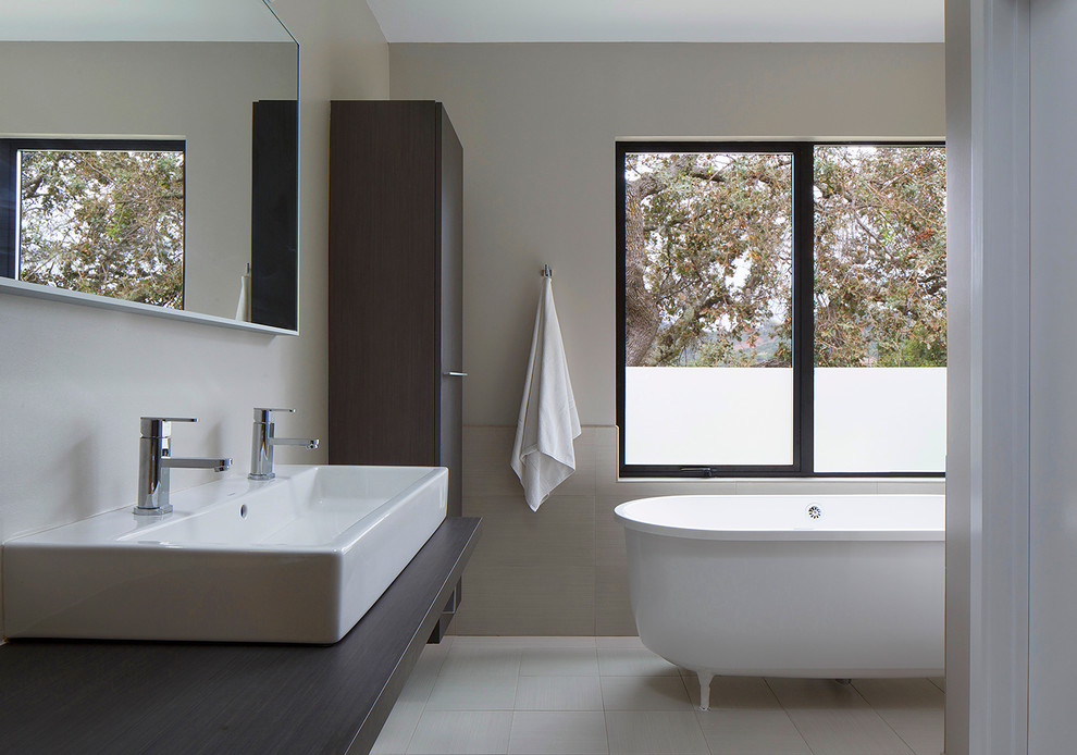 Mid-sized modern master bathroom in San Francisco with a trough sink, flat-panel cabinets, brown cabinets, a freestanding tub, beige tile, porcelain tile, beige walls and porcelain floors.