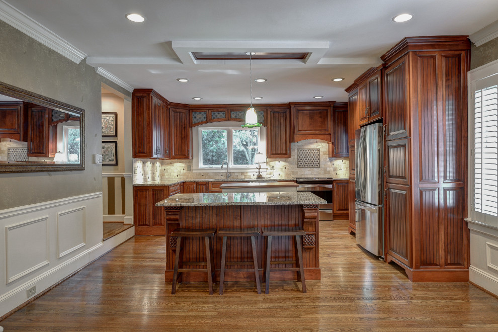 This is an example of a medium sized traditional u-shaped kitchen/diner in Atlanta with raised-panel cabinets, brown cabinets, granite worktops, beige splashback, stainless steel appliances, dark hardwood flooring, multiple islands, brown floors and grey worktops.