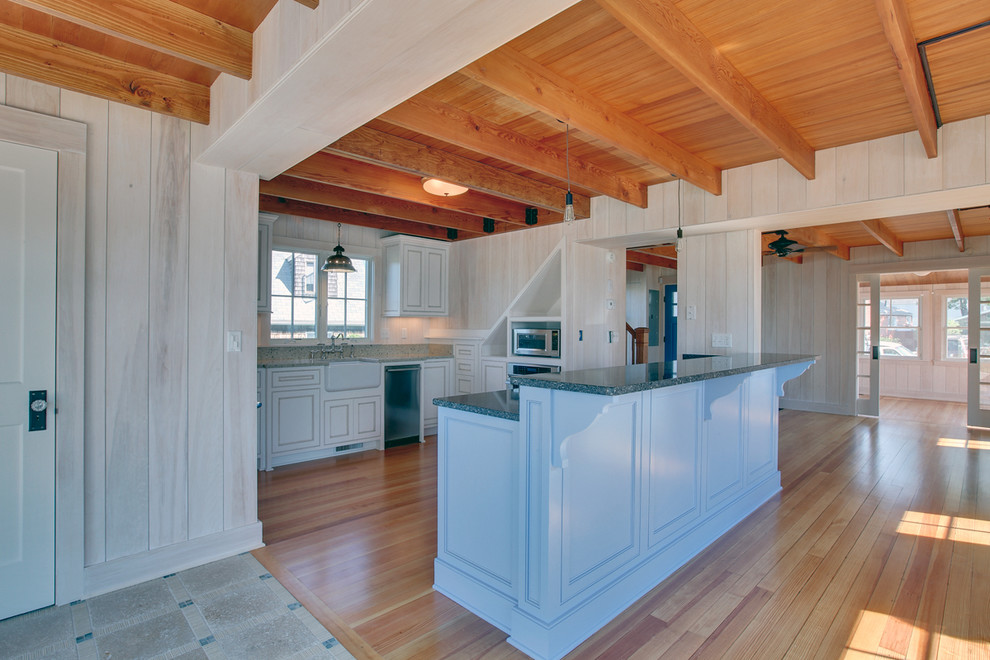 Inspiration for a mid-sized traditional u-shaped eat-in kitchen in New York with a farmhouse sink, beaded inset cabinets, white cabinets, granite benchtops, stainless steel appliances, light hardwood floors and with island.